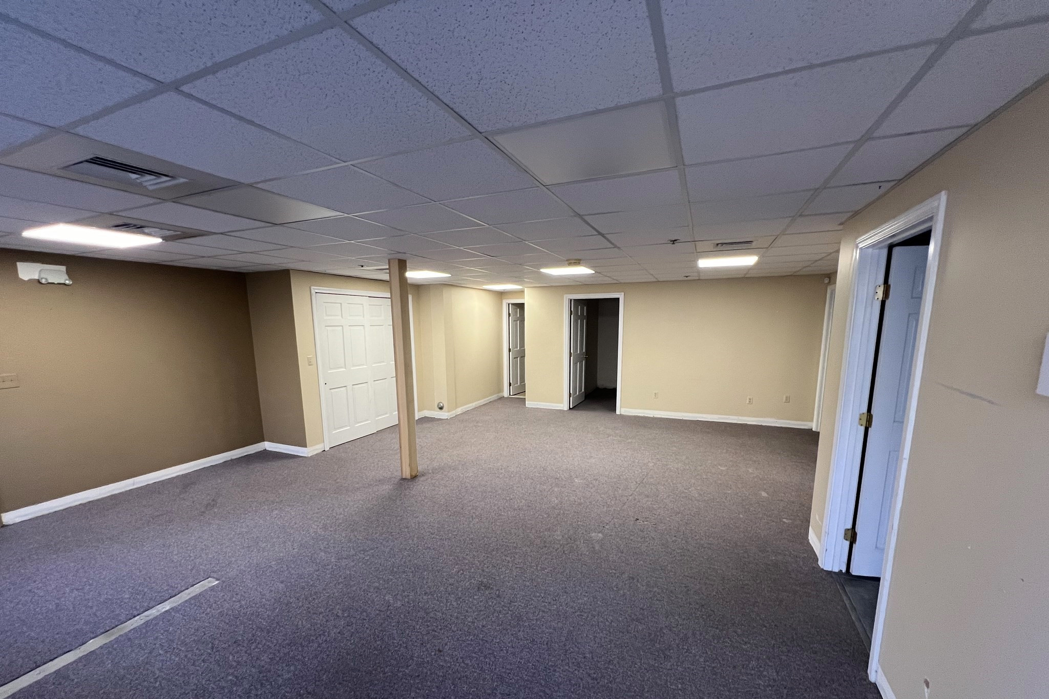 empty office space with tan walls, white trime and a carpeted floor